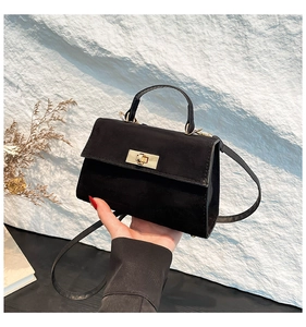 Detail of minimalist black suede crossbody bag with elegant gold twist lock closure