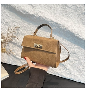 Detail of camel suede mini crossbody bag featuring a classic gold rectangular twist lock