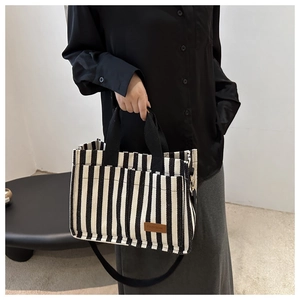 Close-up of black and white striped canvas tote bag showing the brown leather fashion tag