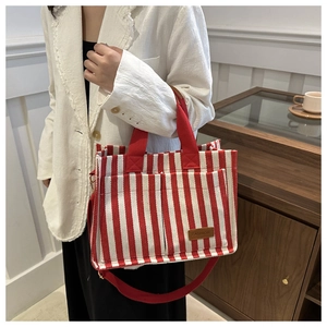 Detail of red and white striped canvas tote featuring a front pocket and leather tag