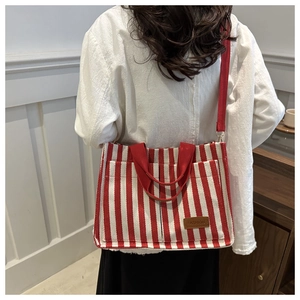 Detail of red and white striped canvas tote bag with adjustable shoulder strap and fashion tag
