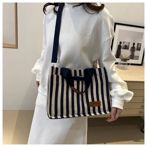 Detail of striped canvas tote bag with adjustable strap in minimalist indoor setting
