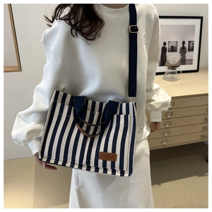 Detail of blue and white striped canvas tote bag showing fashion patch and adjustable strap
