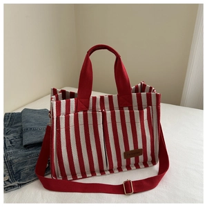Detail of red and white striped canvas tote bag with adjustable shoulder strap and leather tag