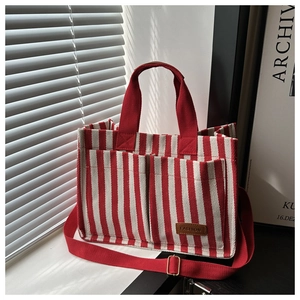 Detail of red and white striped canvas tote featuring front pockets and fashion leather label