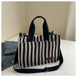 Detailed view of striped canvas tote bag with front pockets and brown leather brand label