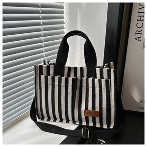 Close-up of black and white striped canvas tote bag with brown leather fashion tag