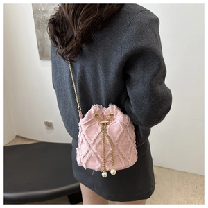Detailed shot of pink denim quilted bucket bag with pearl drawstrings and chain strap