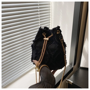 Detail of black tweed bucket bag with quilted patterns and pearl drawstring accents