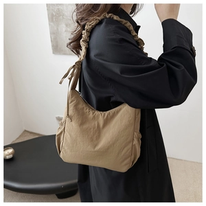 Detail of adjustable drawstring shoulder strap and ruching on khaki crescent tote bag