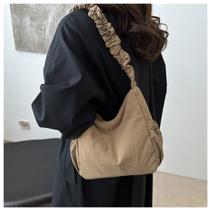 Detail of hobo shoulder bag with ruched strap and earth brown nylon material on model