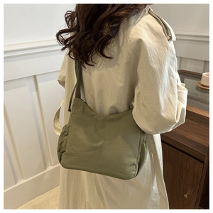 Vue détaillée d'un sac hobo en nylon vert olive porté avec un trench-coat classique