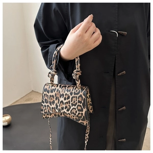 Détail d'un sac à main léopard avec des poignées nouées et une base incurvée élégante