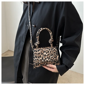 Détail du sac léopard avec base incurvée emblématique et poignée nouée élégante