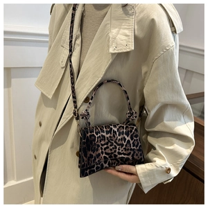 Detail of leopard print handbag with knot handle and adjustable shoulder strap on model