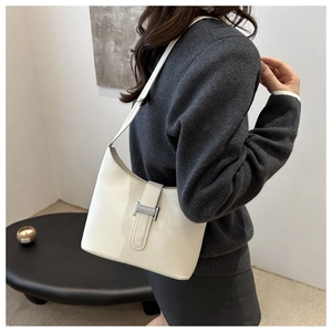 Detailed close-up of white leather shoulder bag with silver H-shaped metal buckle clasp