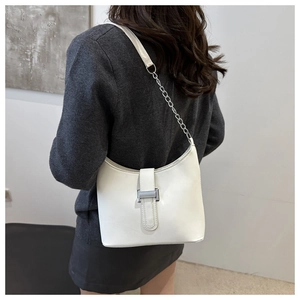 Detail of white leather shoulder bag with silver chain strap and metal buckle accent