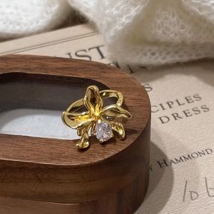 Exaggerated golden geometric flower ring with zircon on vintage book background