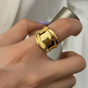 Detailed close-up of wide golden irregular liquid metal ring with glossy finish