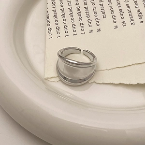 Detailed view of silver wave ring on minimalist ceramic plate with aesthetic paper