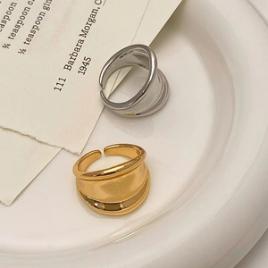Detail of adjustable asymmetric wide rings in gold and silver finish on a ceramic tray