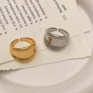 Minimalist wide metal rings in gold and silver finish placed on a white ceramic plate