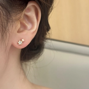 Elegant gold star earrings with zircon inlay shown on model in a soft minimalist style