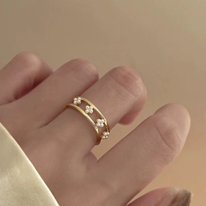 Detail of double-layer gold ring featuring delicate pearl flowers on model hand