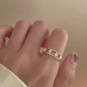 Detail of a gold double-layered ring featuring a delicate four-petal pearl flower design