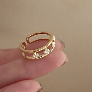 Close-up of dual-layer gold-plated open ring featuring delicate pearl flower details