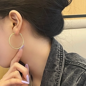 18K gold-plated circular spiral hoop earrings with textured finish on female model