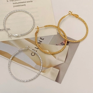 Flat lay of textured gold and silver hoop earrings on minimalist white background