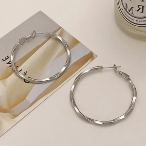 Macro shot of silver spiral twist hoop earrings with detailed metallic texture