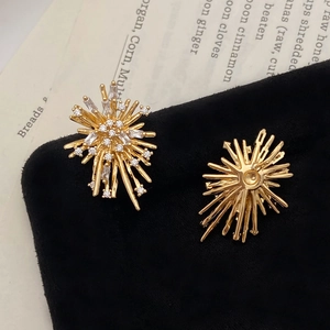 Elegant gold fireworks stud earrings with white zircon accents on vintage book background