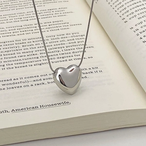 Detailed view of a silver heart pendant necklace on an open book with fine snake chain