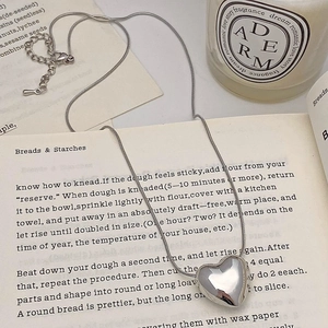 Polished silver heart pendant on a delicate snake chain resting on vintage books