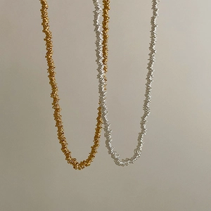 Detailed view of beaded necklaces featuring metallic gold and silver textured surfaces