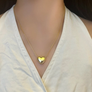 Elegant gold heart pendant necklace with a polished snake chain worn on a model