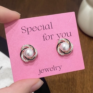 Close-up of pearl stud earrings with black and white spiral texture and fine zircon inlay