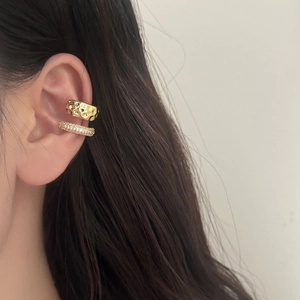 Detail of double-layered gold ear cuffs with cubic zirconia and hammered metal finish