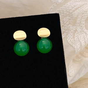 Detailed view of green chalcedony earrings with irregular gold metal studs on black velvet