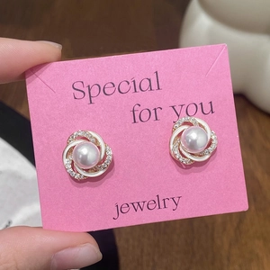 Macro shot of pearl stud earrings with white enamel twist and sparkling rhinestone details