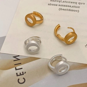Detail view of brushed hollow circular earrings in matte gold and silver finish