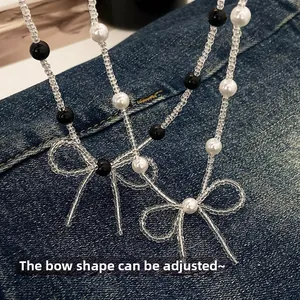 Detail of beaded necklace with adjustable crystal bows on a denim texture background