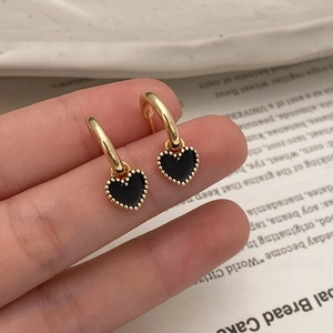 Détail de la boucle d'oreille cœur avec bord perlé doré et émail noir sur anneau