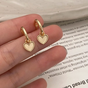 Gros plan détaillé des boucles d'oreilles cœur doré avec bords perlés milgrain élégants