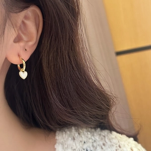 Détail d'une créole cœur dorée avec insert blanc et bord perlé sur un mannequin
