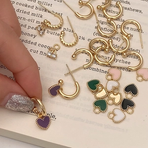 Détail de boucles d'oreilles cœur dorées et breloques cerise sur fond de livre