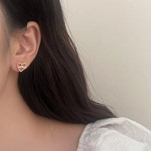 Gros plan détaillé de boucles d'oreilles cœur dorées avec perles portées par un mannequin