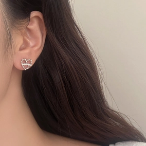 Gros plan détaillé des boucles d'oreilles cœur en perles portées par un mannequin